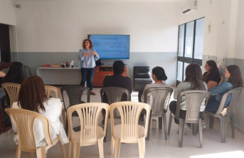 A woman standing in a classroom speaking to a group of seated girls