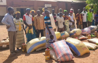 Group of African men and women waiting in line with large food packages on the ground in front of them