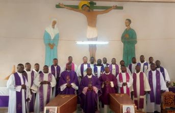 Large group of African men wearing religious clothing standing behind two coffins