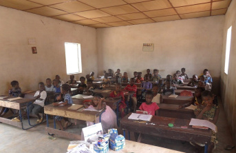 Basic classroom with wooden desks and African school children