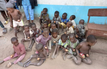 Several young African children sitting on the floor, each holding food