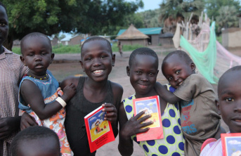 Group of young African children smiling and holding children's bibles
