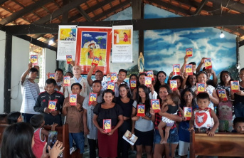 Group of people holding a children's bible inside a church with wooden beams