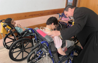 A priest helping 2 boys in wheelchairs