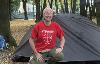 Eileen Murray kneeling in front of her tent in the Cascata delle Marmore forest in Italy