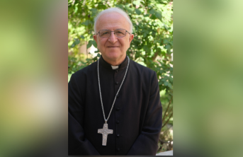 Bishop Shomali in front of a green tree