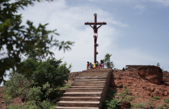 Children sitting around the foot of a Cross