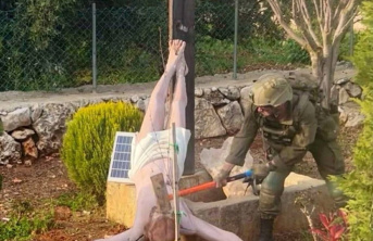 IDF soldier hitting crucifix with hammer