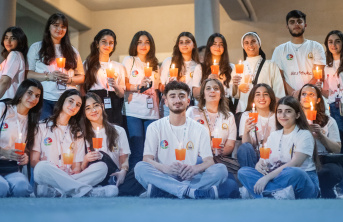 University students in Iraq sitting and standing together holding candles