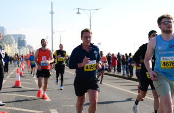 A number of marathon runners running along a road fundraising for charity