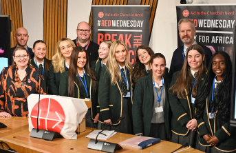 Students and teachers standing in front of advocacy banners behind a desk