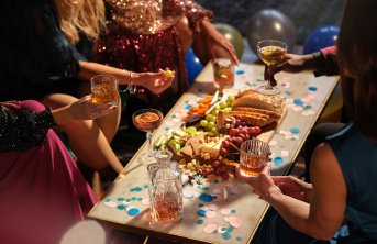 Dinner party table of food with people around holding glasses of drinks