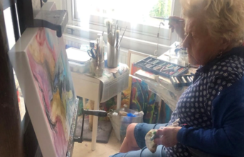 Artist Elizabeth Duncan Meyer sitting painting in her studio