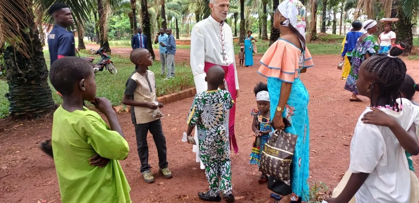 A bishop talking to an African woman surrounded by children