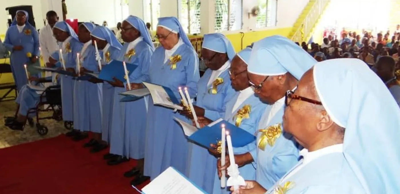 Several sisters standing side-by-side holding folders and candles dressed in blue