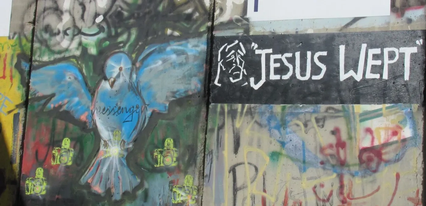 Graffiti on a wall in Bethlehem depicting a large blue bird next to the words 'Jesus Wept'
