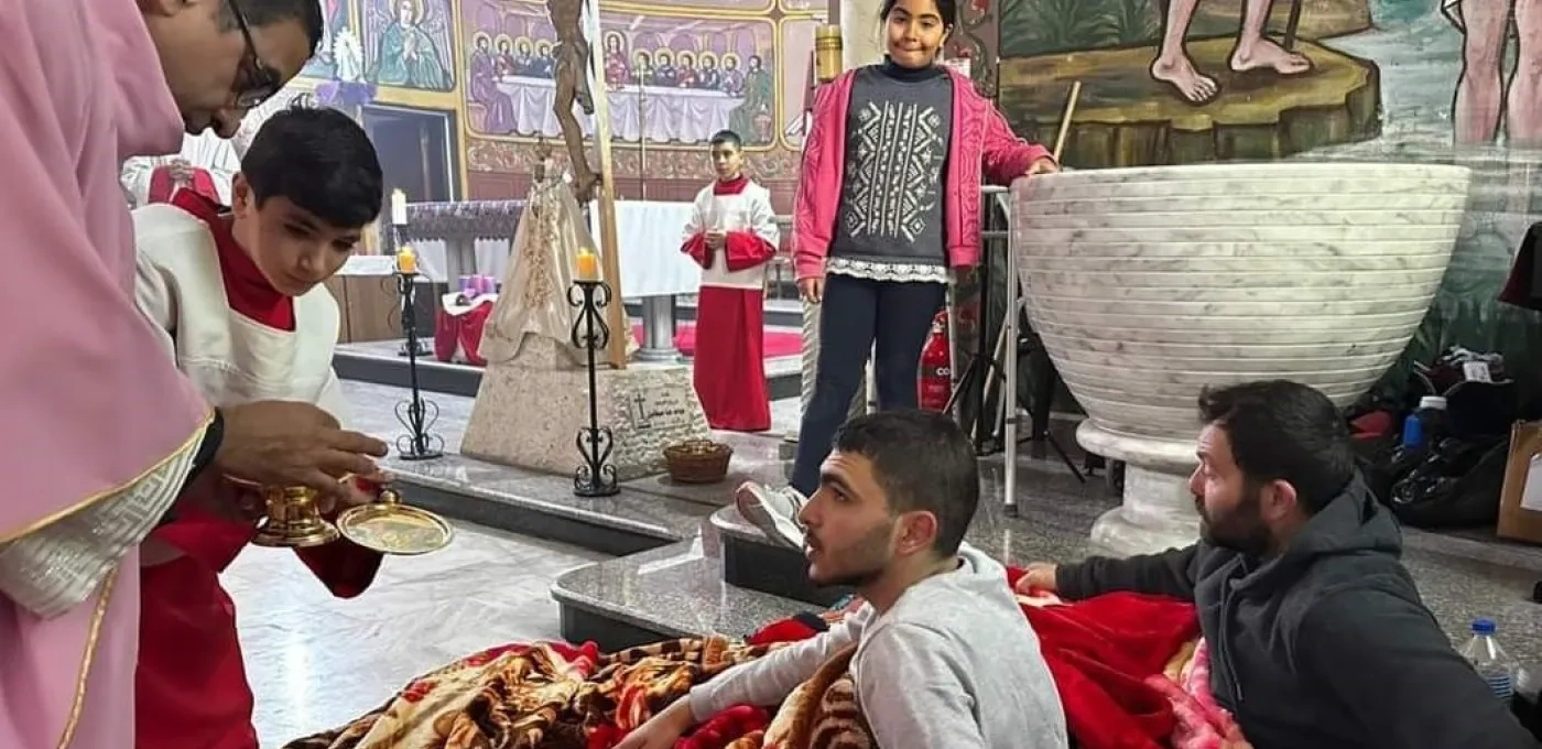 Two men sitting on the floor of a church receiving communion with a young girl watching