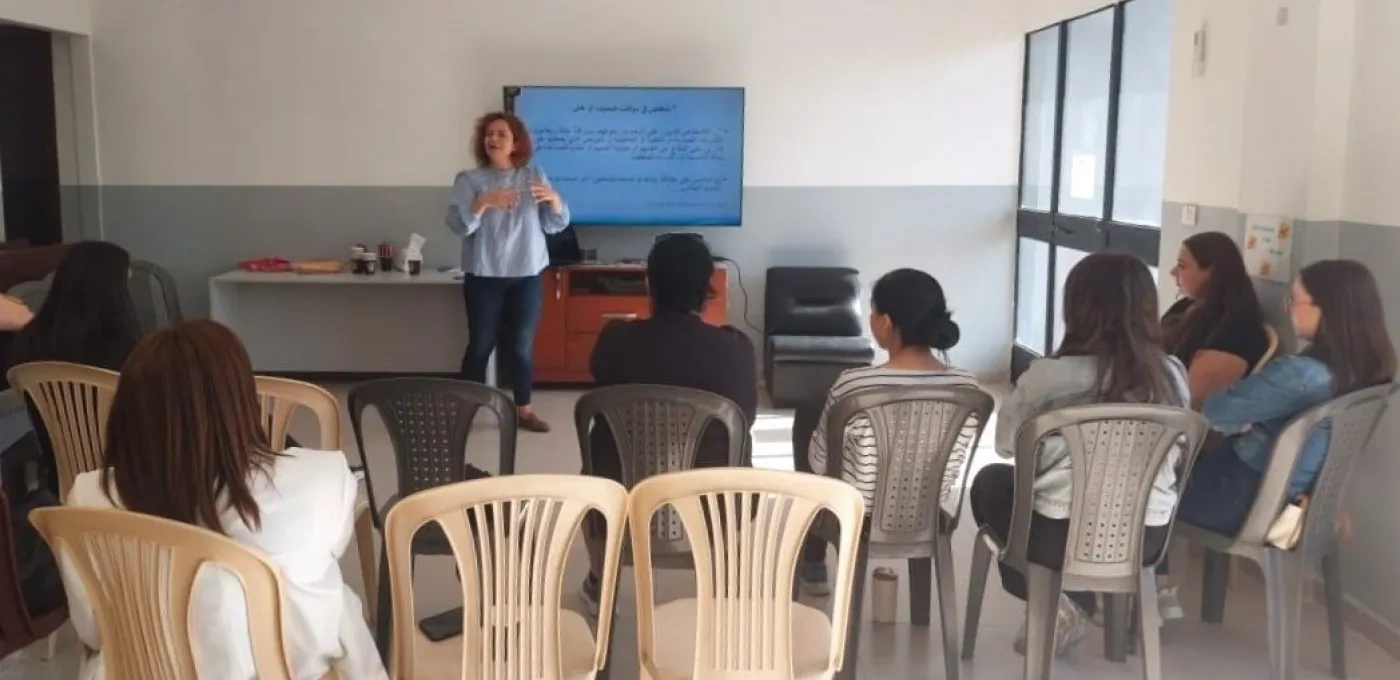 A woman standing in a classroom speaking to a group of seated girls
