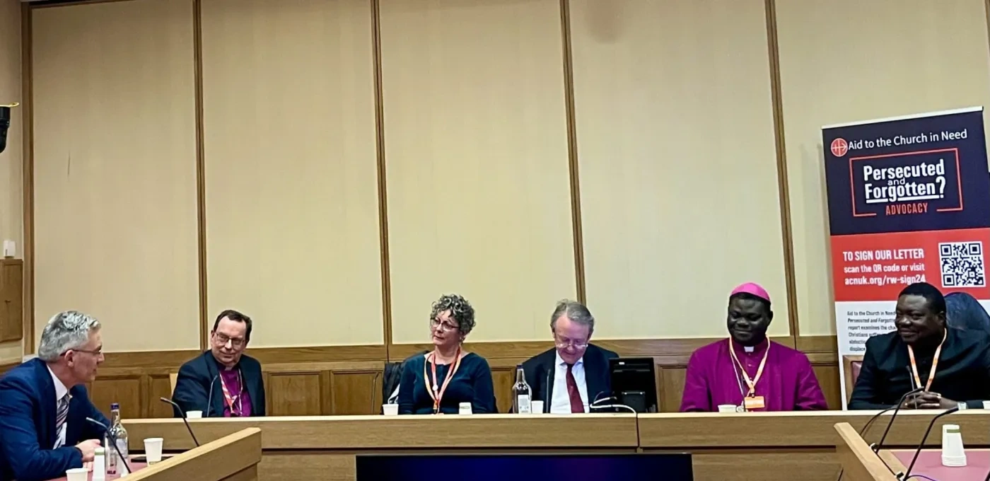 Group of people sitting around a table within parliament including a Bishop and Father from Nigeria