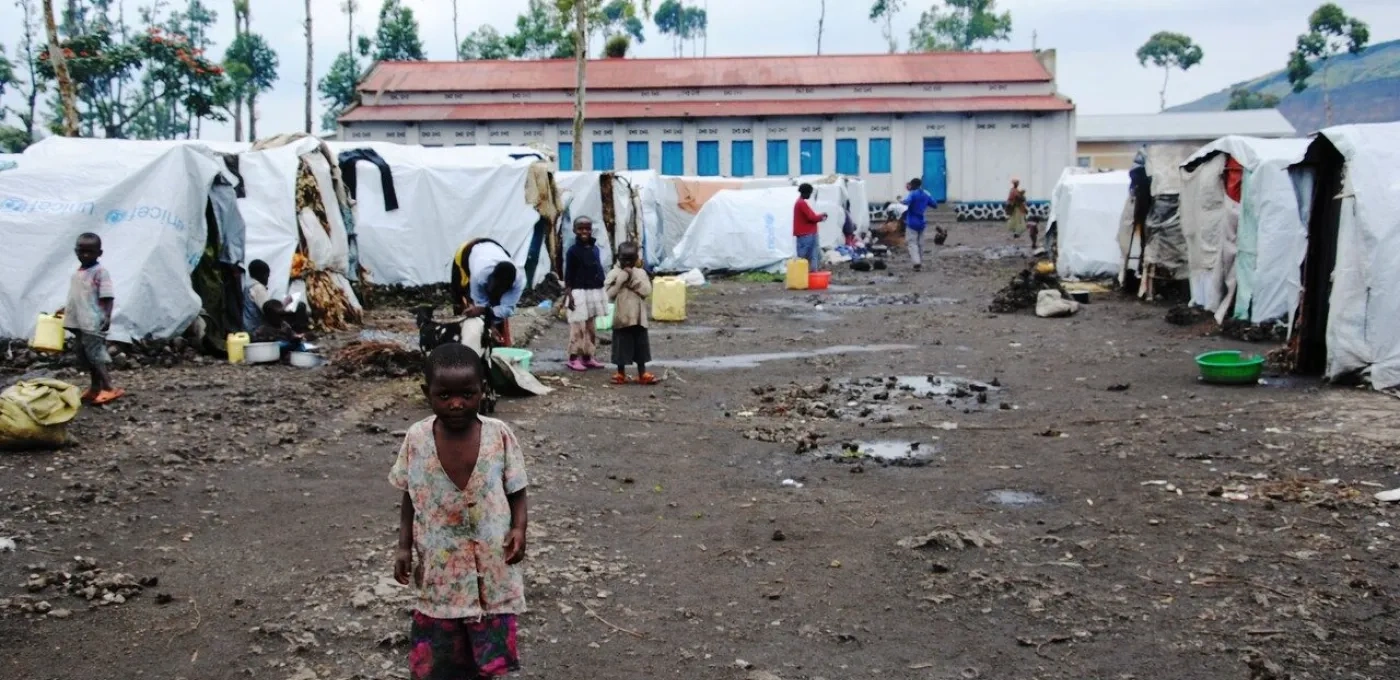 A small African child standing in the middle of a displacement camp