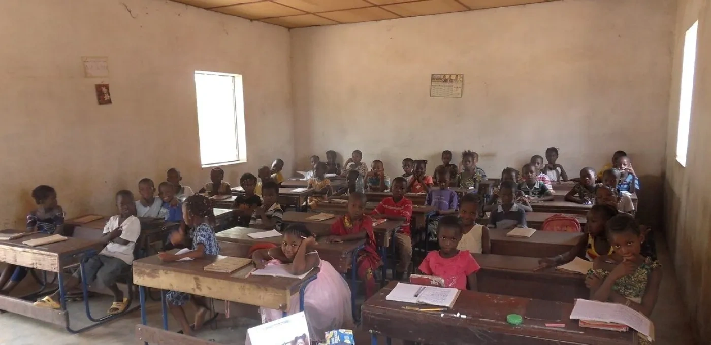 Basic classroom with wooden desks and African school children