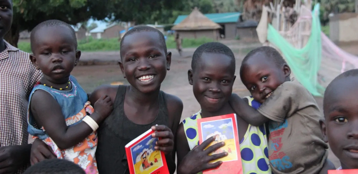 Group of young African children smiling and holding children's bibles