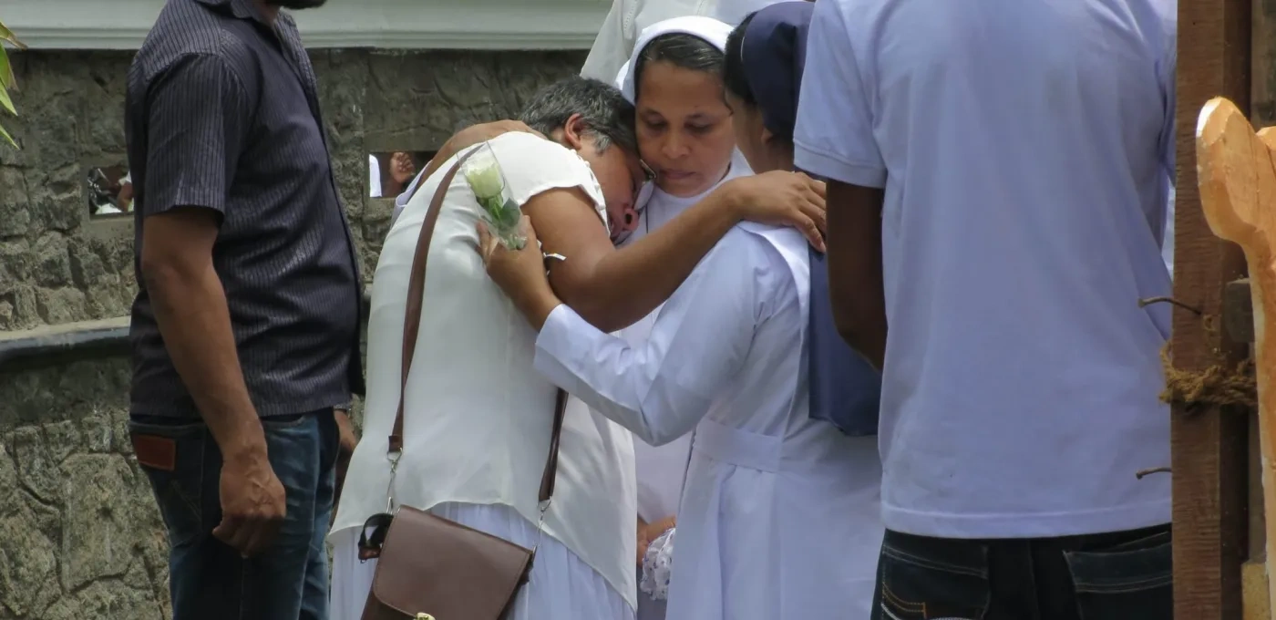 Sister solemnly hugging a family after Mass