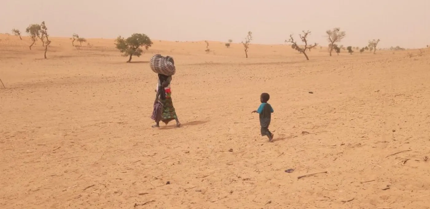 Woman and child walking across a desert