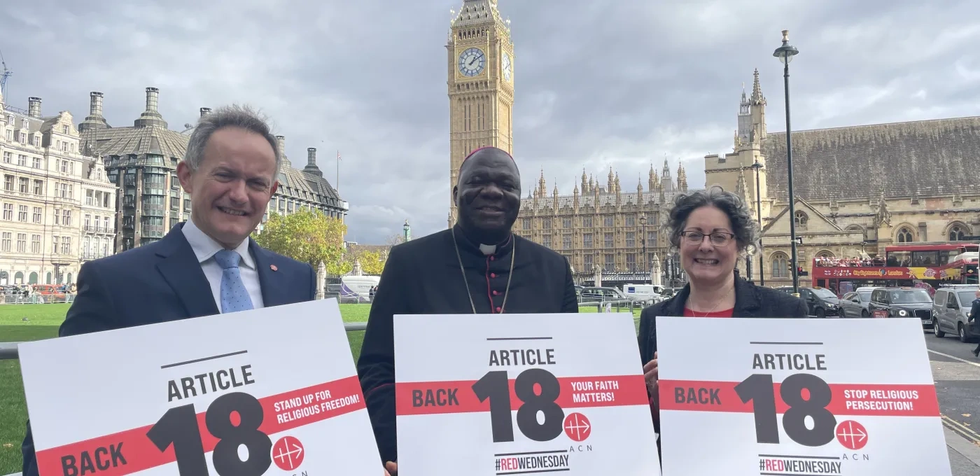 John Pontifex, Bishop John Bakeni and Dr Caroline Hull in front of Parliament holding up signs that read back article 18