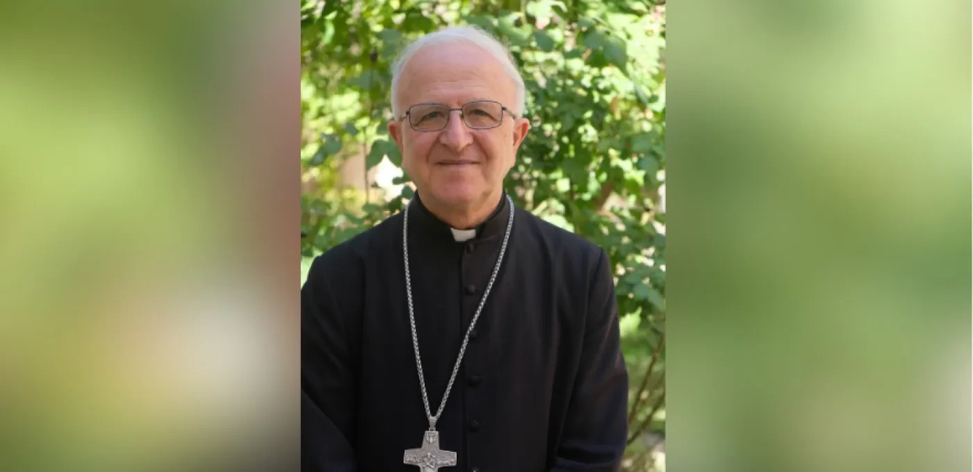 Bishop Shomali in front of a green tree