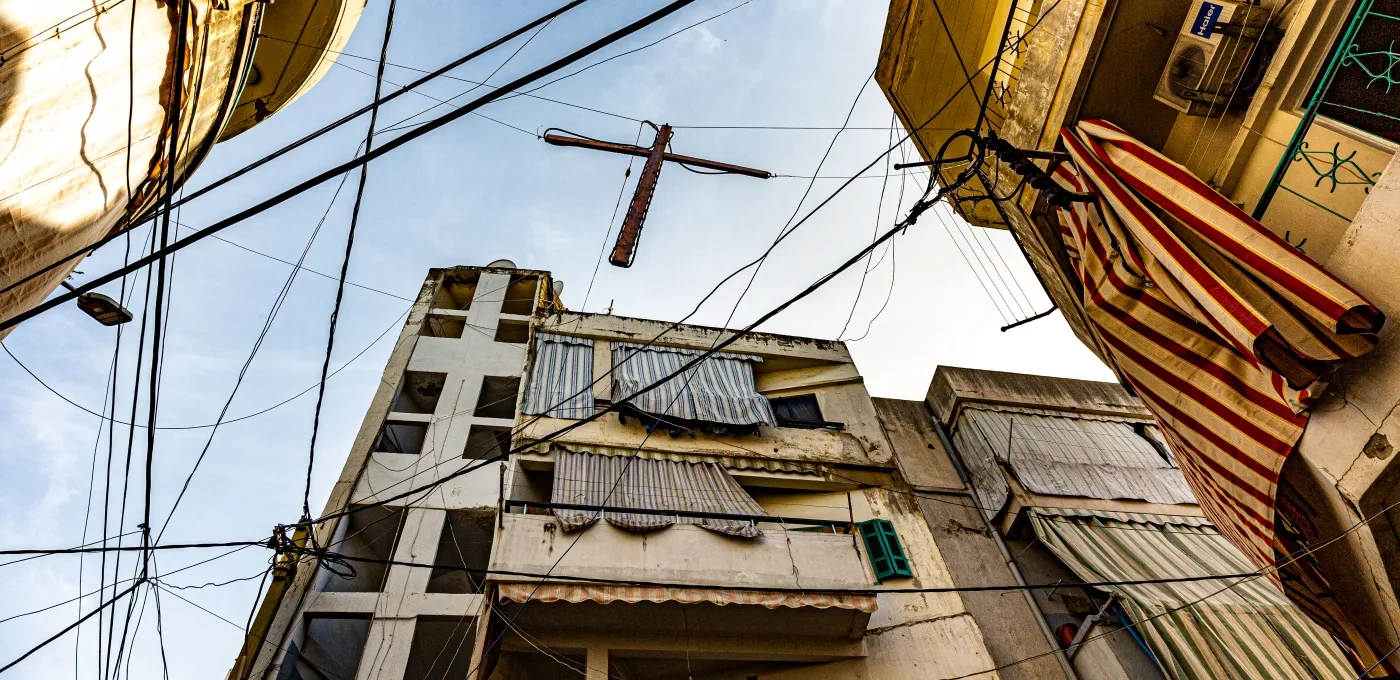 A wooden cross hanging next to electricity wires in Bourj Hammoud, Beirut, symbolizing the resilience of Lebanese Christians amid ongoing conflict