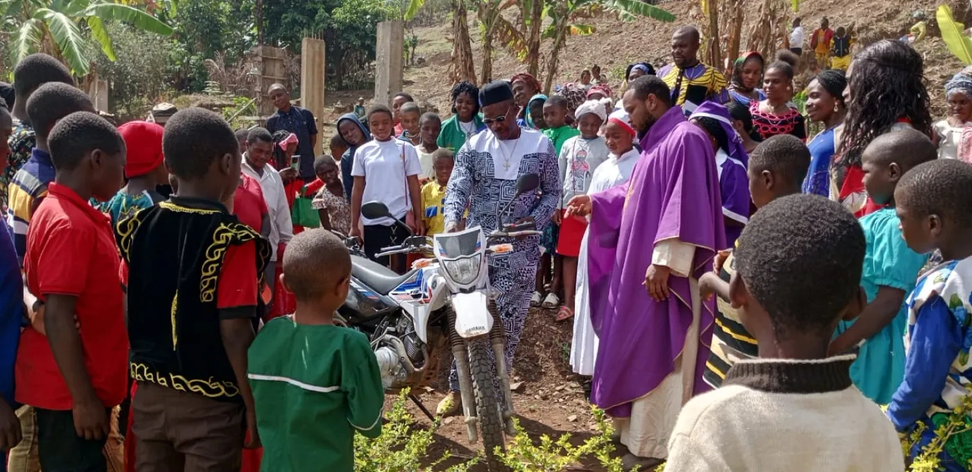 Parishioners and a priest gathered around the new motorbike in Bamenda