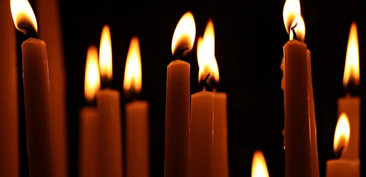 A collection of lit candles in darkness