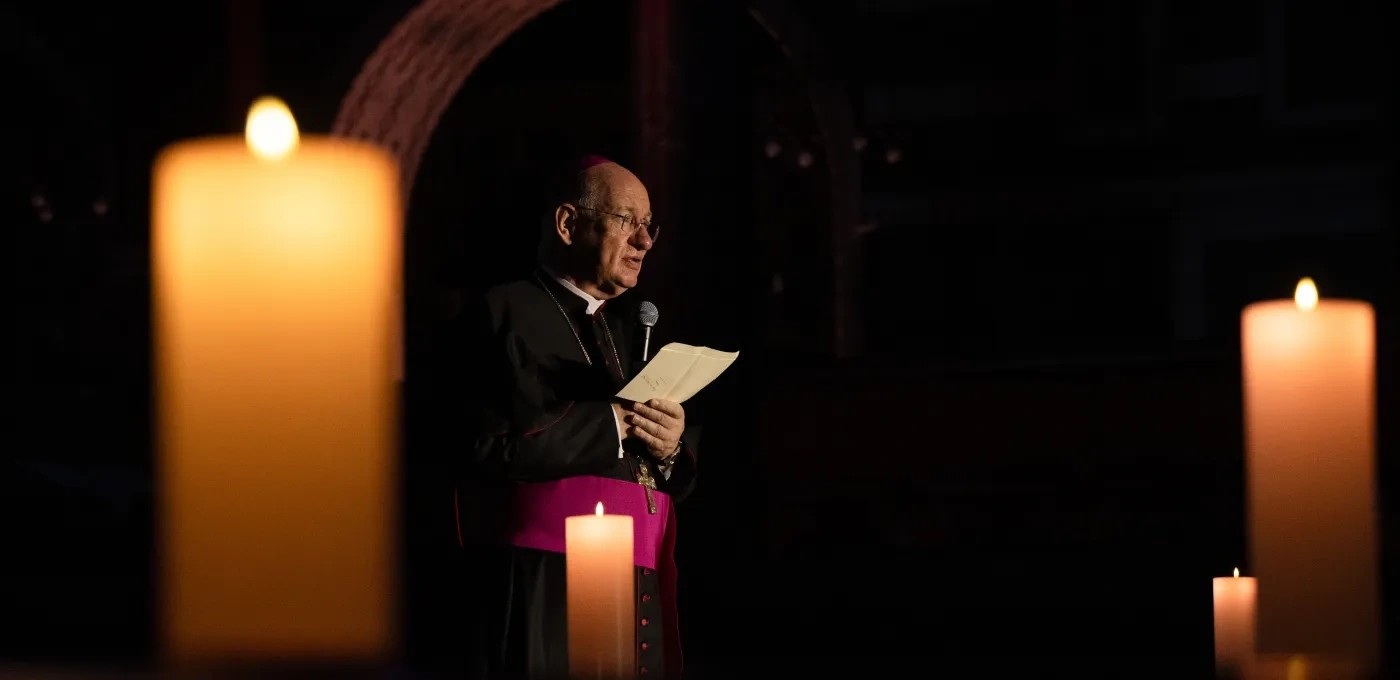 an Archbishop standing in a candle lit room