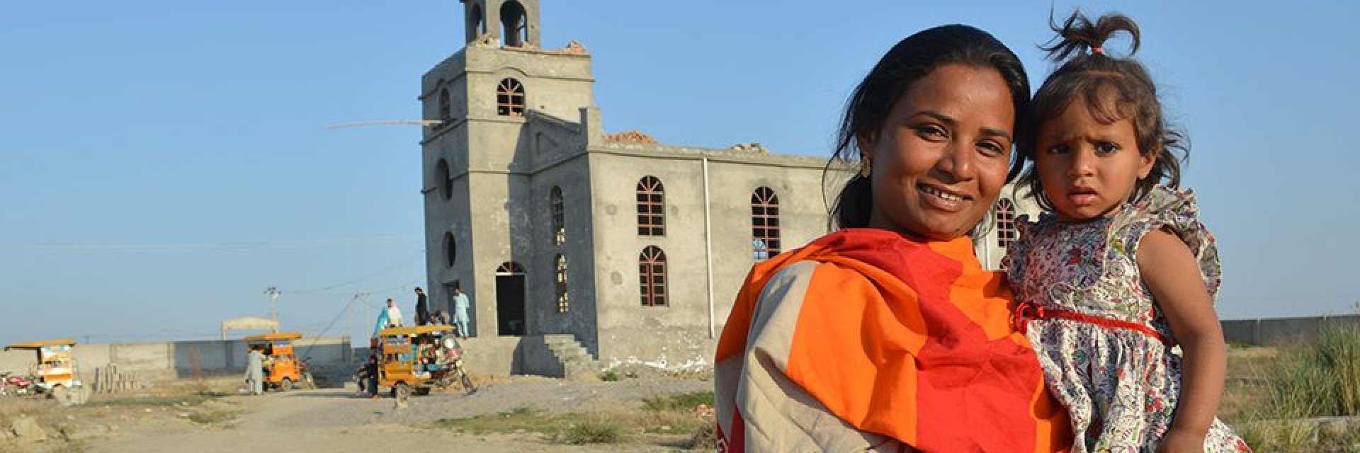 A woman and a child standing in front of a church being built