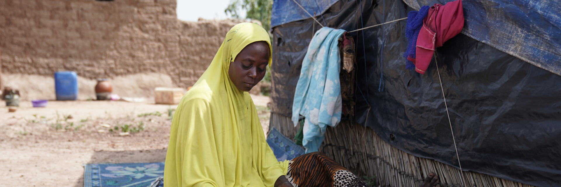 A woman sitting outside a tent in a IDP camp