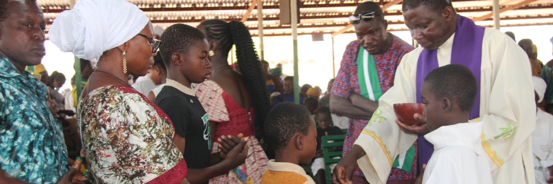 Priest giving communion in Burkina Faso