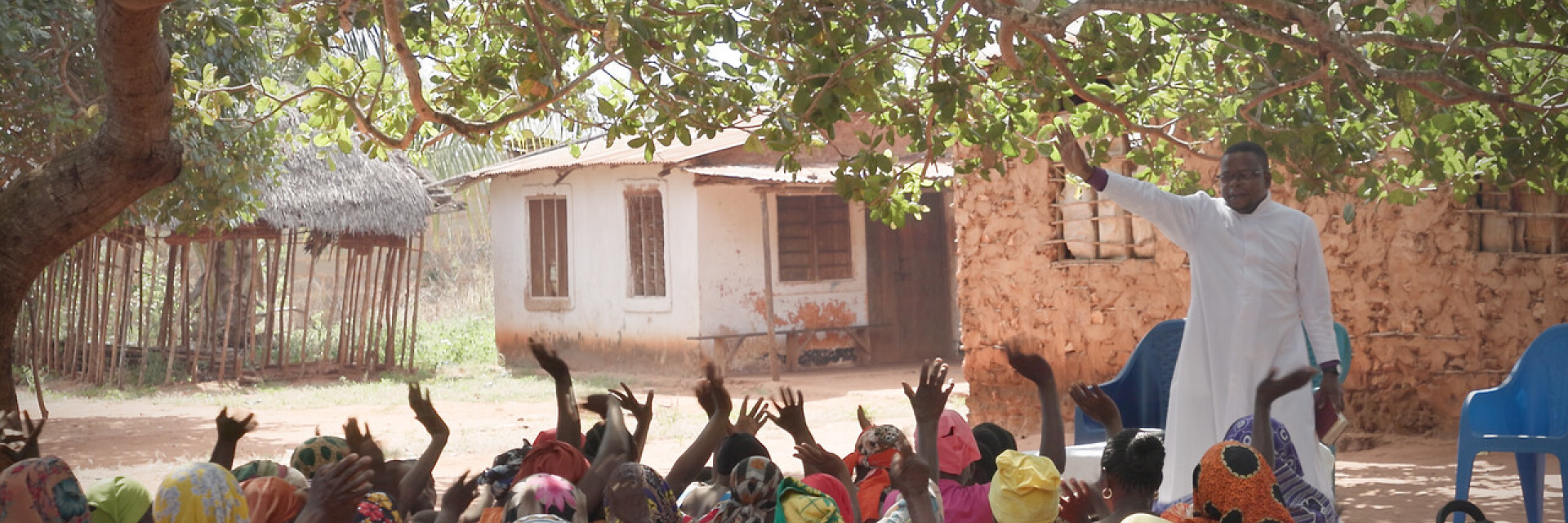 Catechist speaking to a group of faithful Christians in the shade