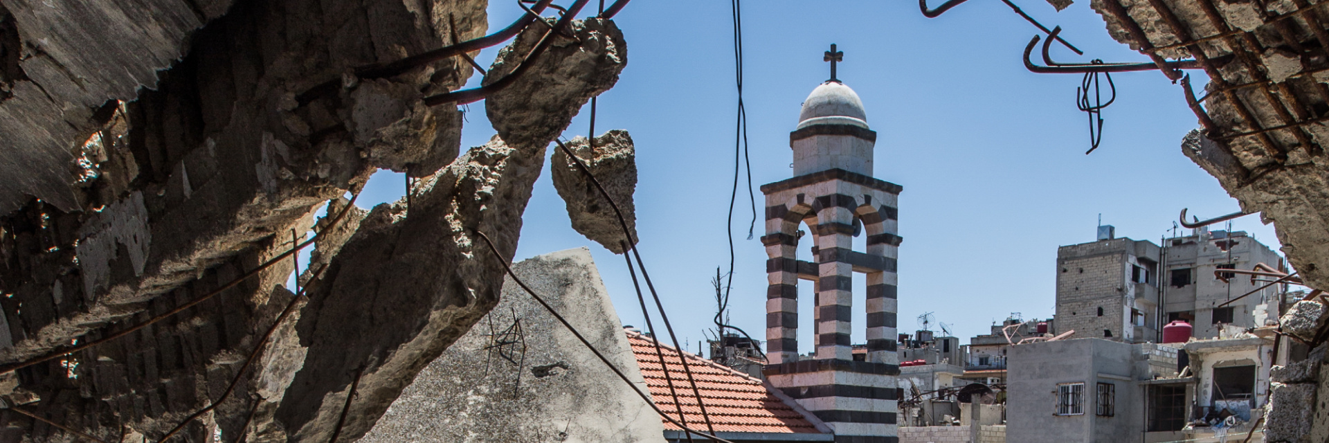 A church bell tower seen through rubble after an attack