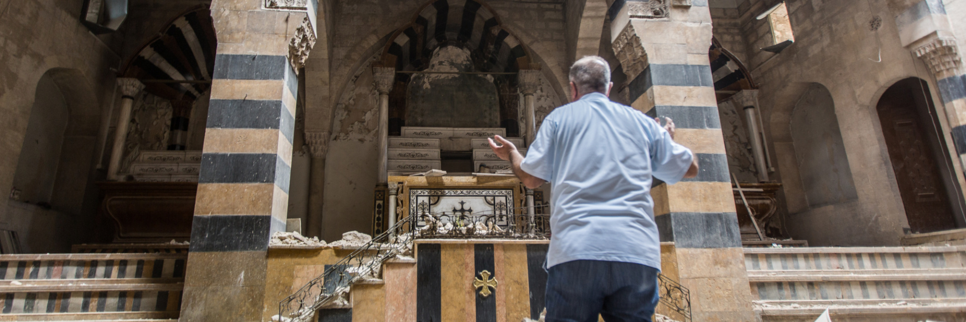 A Christian man praying in front of a destroyed altar