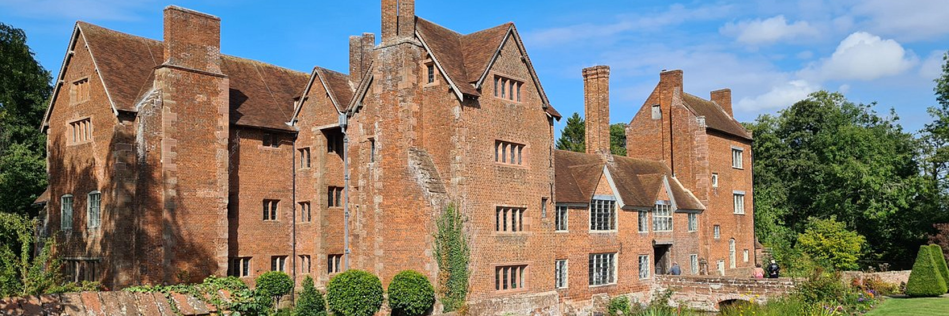A classic large British manor house  with green lawn out front of the property