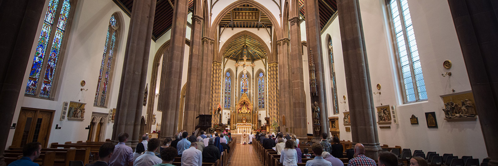 The interior of a Cathedral with parisheners worshipping at the back
