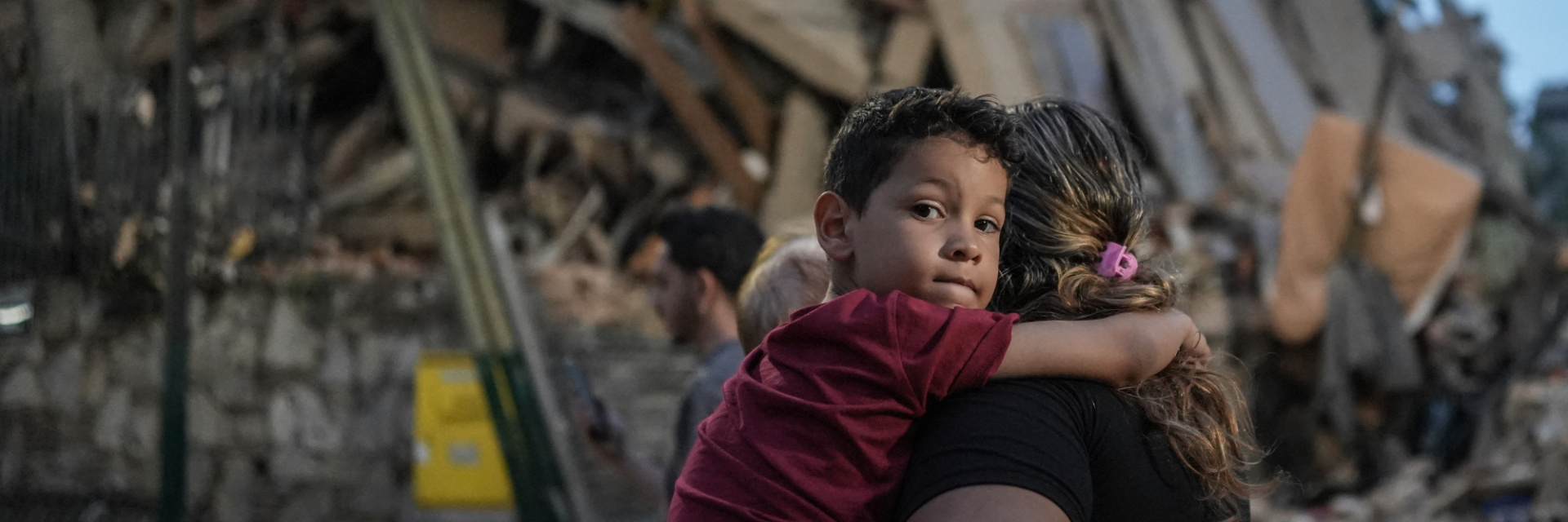 A young boy with his mother standing in front of destroyed building caused by earthquake in Venezuela