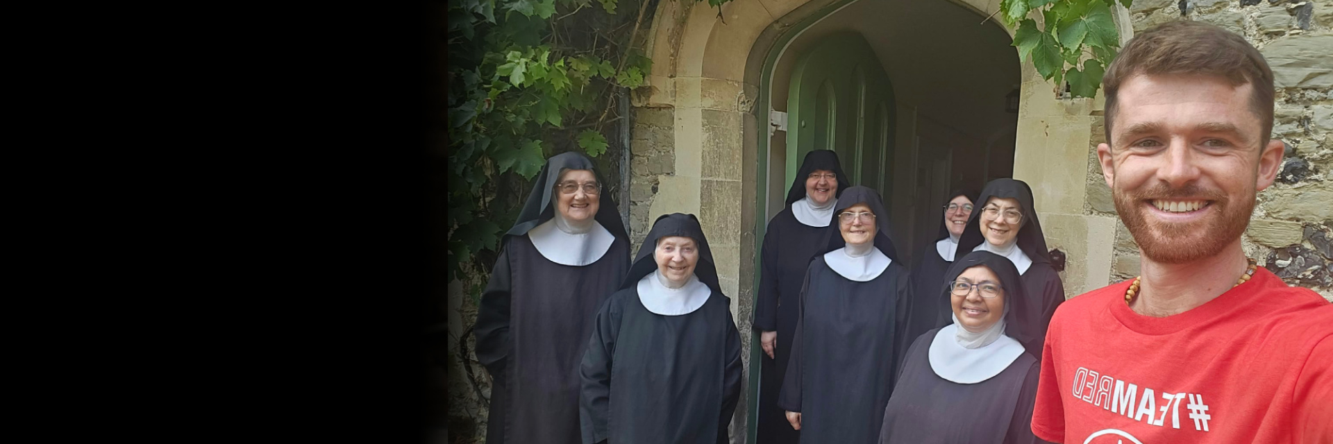 A man standing with a group of nuns outside of a church