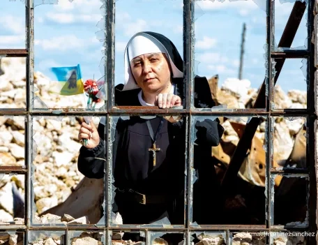 A sister looking through a destroyed window of a Catholic church in Ukraine