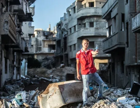 A Christian man standing on a pile of rubble
