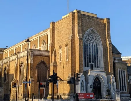 A Cathedral with traffic crossing in front of it's entrance along with a red banner
