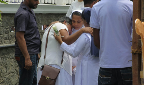 Sister solemnly hugging a family after Mass
