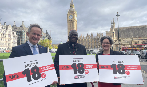 John Pontifex, Bishop John Bakeni and Dr Caroline Hull in front of Parliament holding up signs that read back article 18 