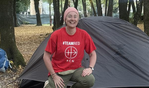 Eileen Murray kneeling in front of her tent in the Cascata delle Marmore forest in Italy